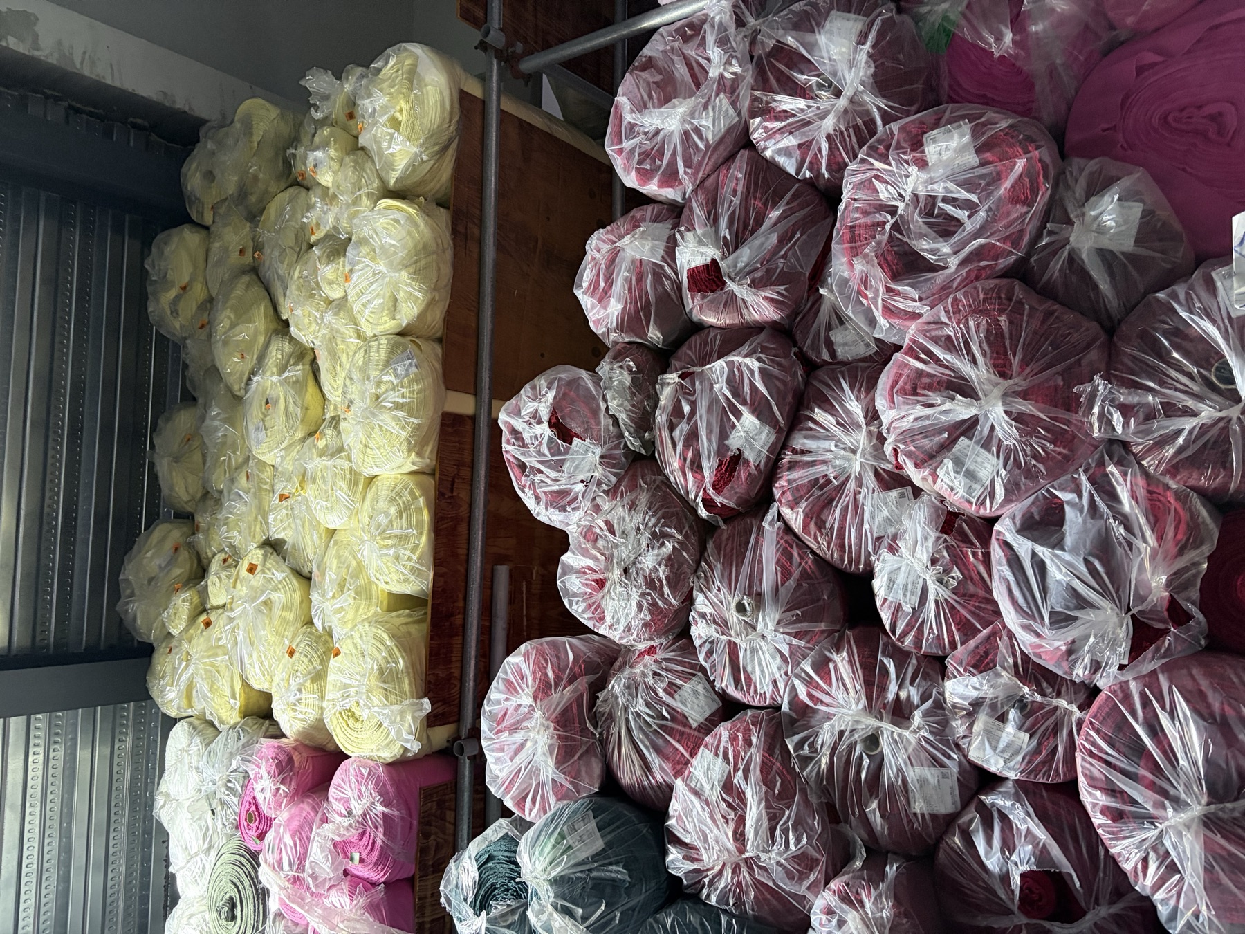 Yellow and red surplus fabric rolls stored by color