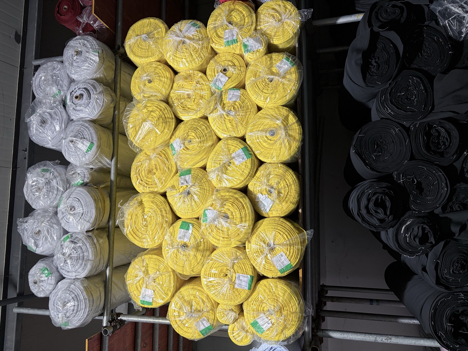 Yellow, white and black fabric rolls on warehouse racks